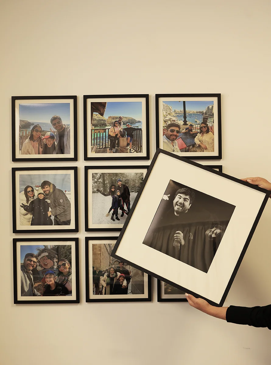 Quadro FrameU preto com fotografia a preto e branco e passe-partout, junto a uma composição na parede